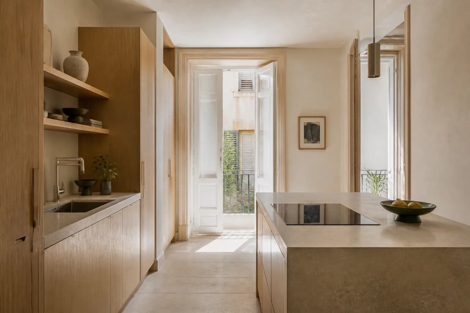 Cocina reformada con mobiliario de roble claro, encimera de piedra y luz mediterránea